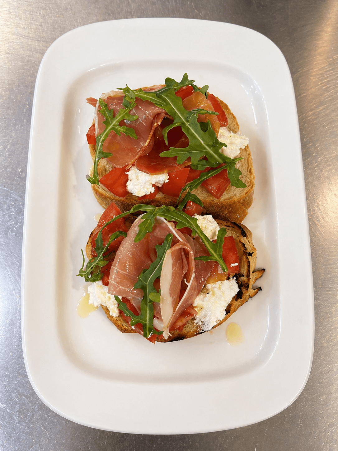 Orama bruschetta with prosciutto, tomato, ricotta and arugula